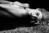 Černobílá fotografie nahé ženy ležící na trávě