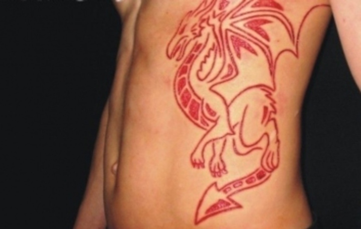 Fotografie nahého ženského těla s červeným tetováním na levém boku