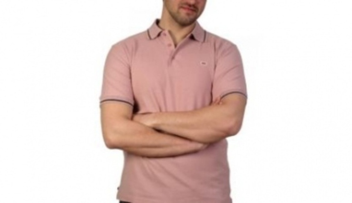 Fotografie stojícího muže v růžové košili se založenými rukama
