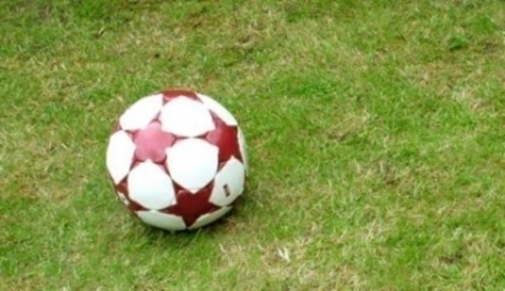 Fotbalový míč s červenými hvězdami ležící na fotbalovém hřišti