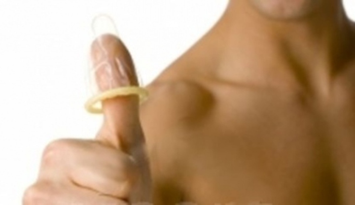 Fotografie muže s detailem na palec, kde je umístěn kondom