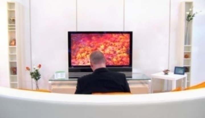 Záběr na muže sledující televizor z pohovky