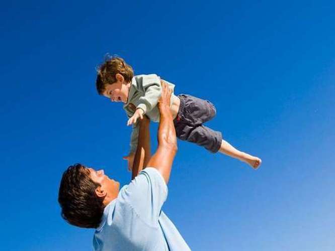 Fotografie muže, který drží ve vzduchu dítě