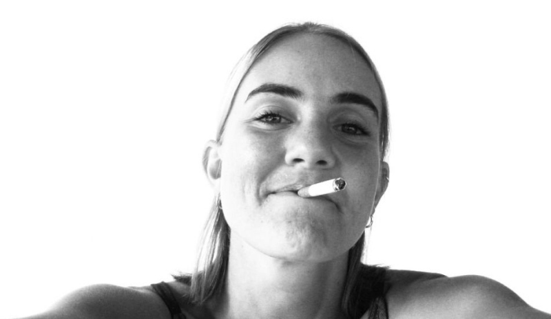 Černobílá fotografie ženy s cigaretou v puse