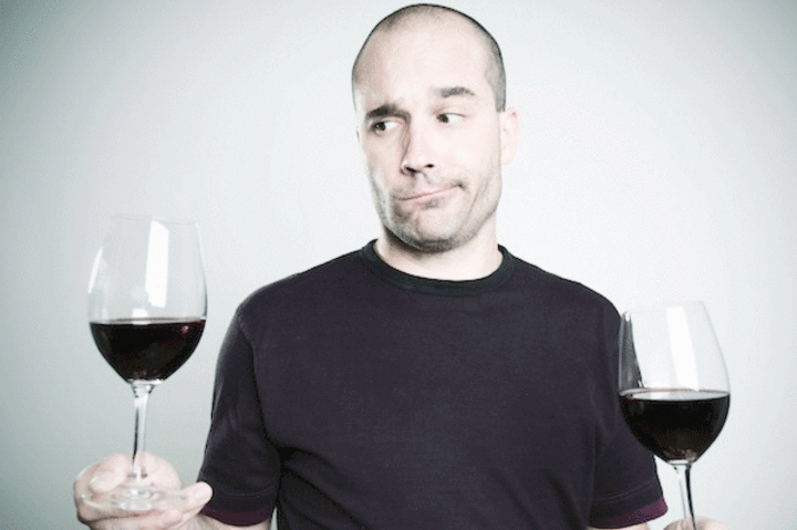 Fotografie muže držící dvě sklenice s červeným vínem