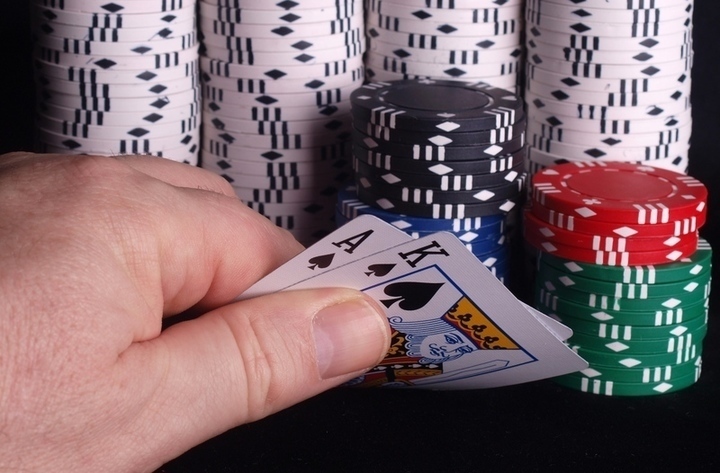 Ruka držící karty před pokerovými žetony