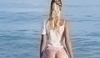 Fotografie blondýny stojící ve vodě, která je otočená zády