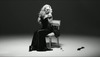 Natalie Portman sedí na židli v dlouhých černých šatech