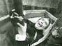 Fotografie muže s upiřími zuby ležícího v rakvi